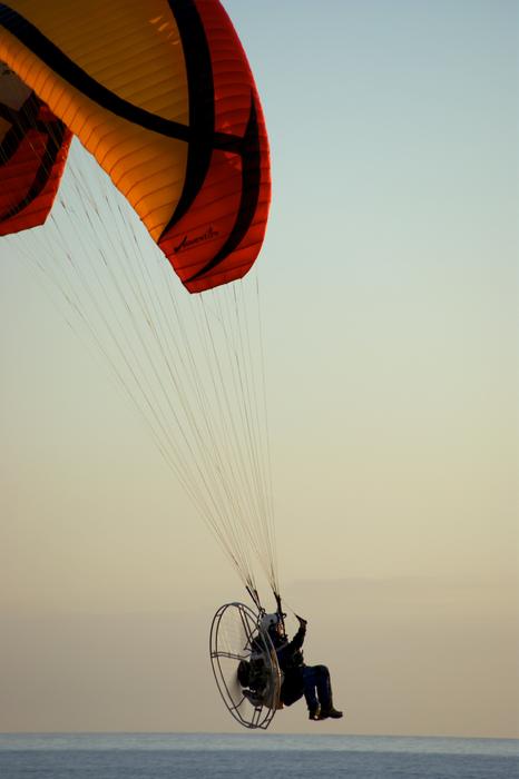 Paraglider with a motor over the sea at dusk