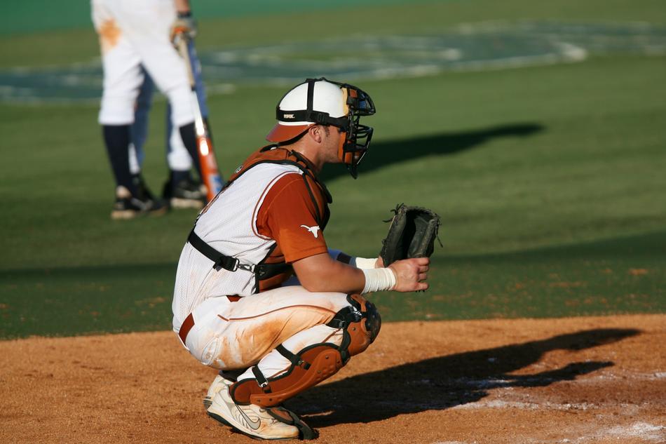 Baseball catcher near the other players, on the field, in sunlight