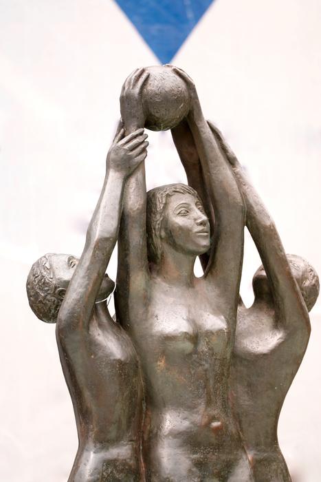 Shiny statues of the women with ball, under the blue sky