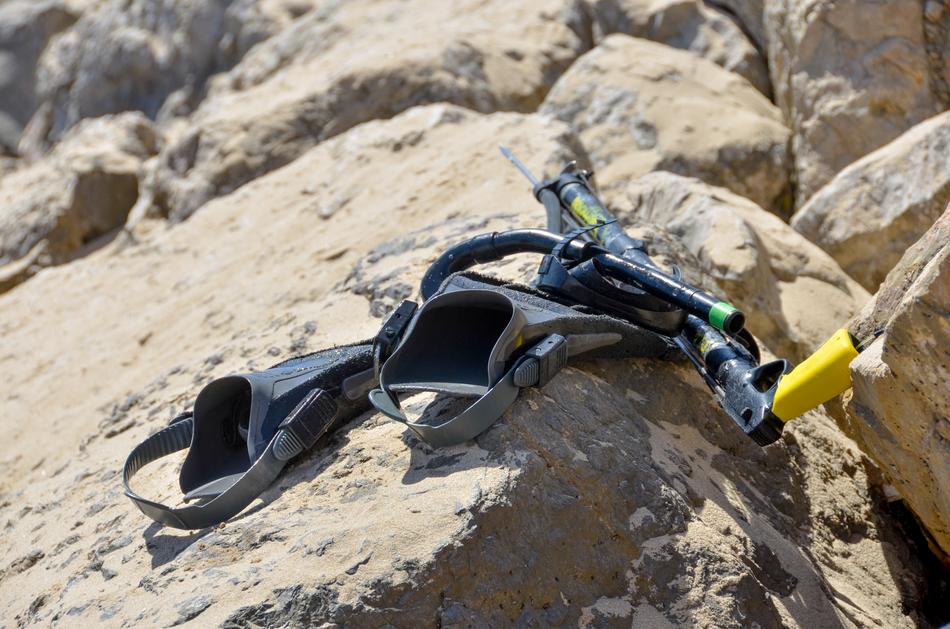fins and weapon for spearfishing on a stone