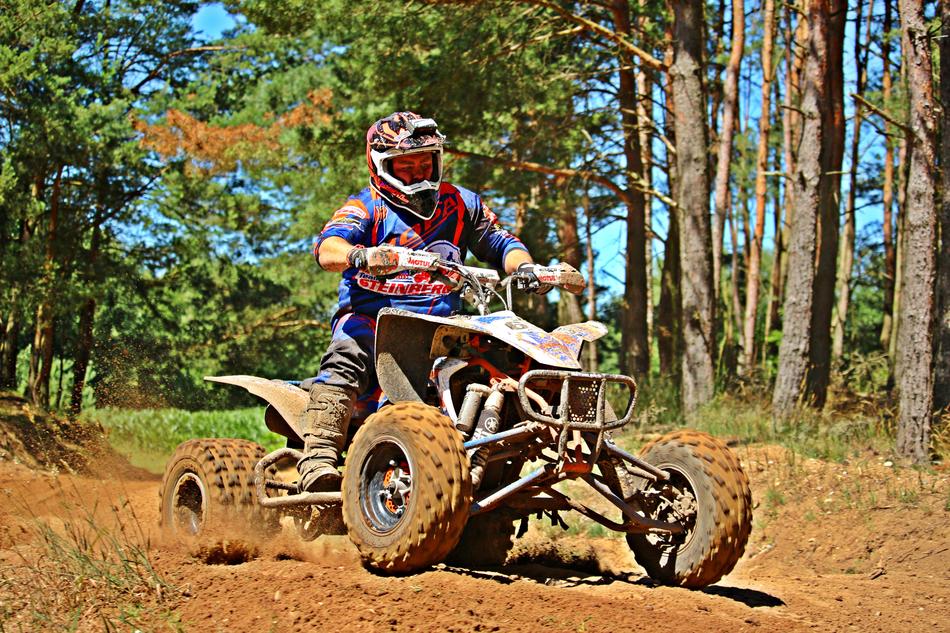 a man on a quad bike on the road near the trees