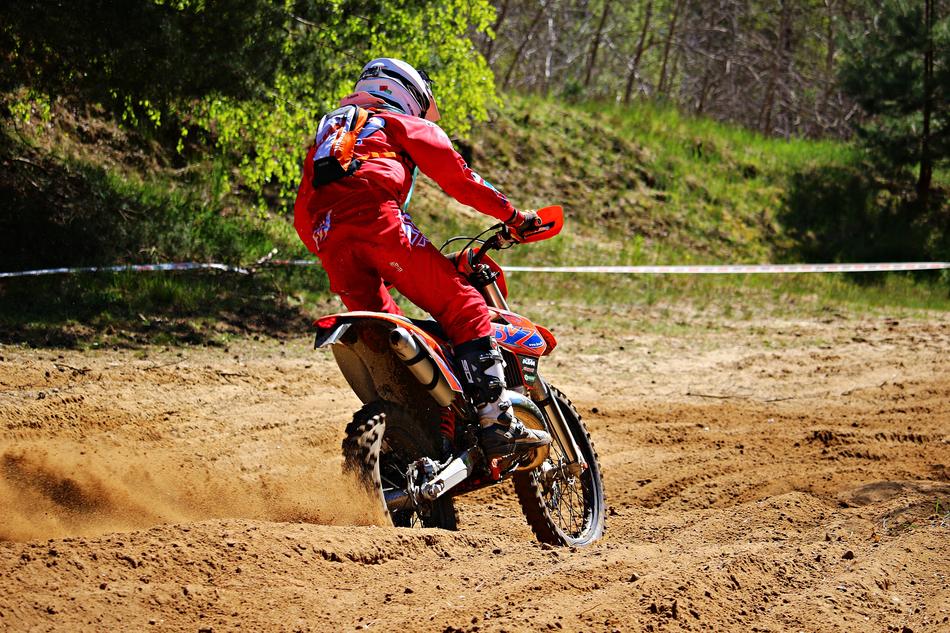 motorcycle racer in red uniform racing on the sand