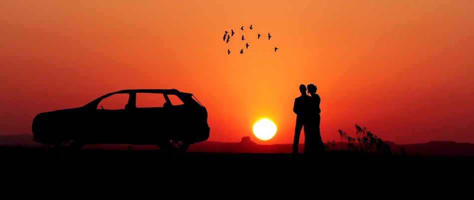 silhouette of couple standing beside of car at sunset