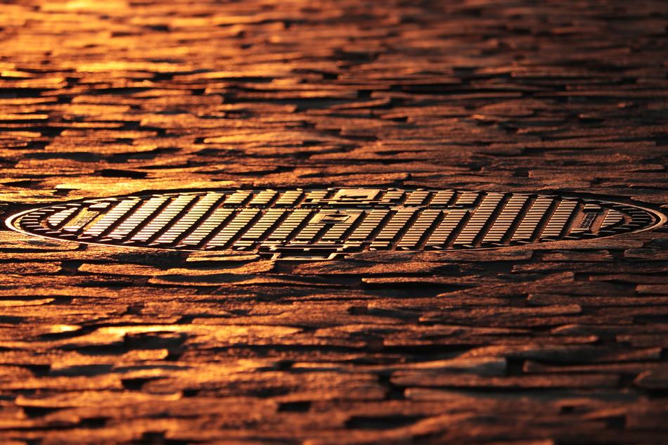 manhole cover and pavers according to the rays of the evening sun