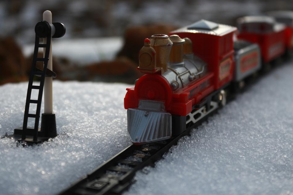 Model of the red train, on the railway, among the snow, in the winter