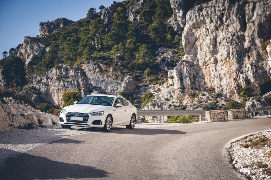 Beautiful, white car on the winding road on the mountain with green plants