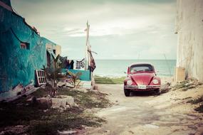 Old red Volkswagen Car parked on street at seaside