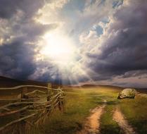 storm clouds and sunbeams over a rural field