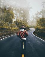 man on a highway in a foggy forest