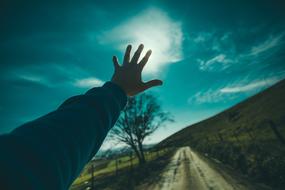 guy's hand on the background of the sun in the sky