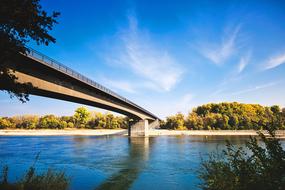 Beautiful and colorful landscape with the bridge, above the Rhine river, among the colorful and beautiful trees, under the blue sky with white clouds