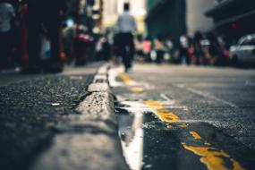 Close-up of a puddle on the road, with people, among the buildings