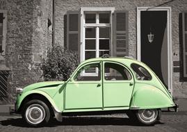 Bright green Citroen car with the black and white photo of the building on background