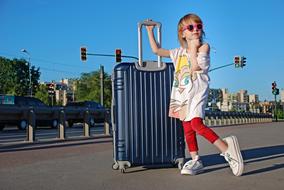 Blonde girl with the suitcase and glasses, posing on the street, near the toad