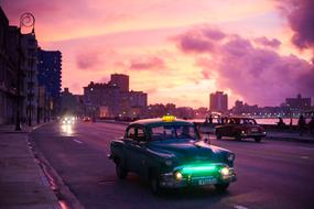 green retro taxi rides along the promenade in Havana, Cuba