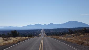 endless asphalt highway with mountains in the background