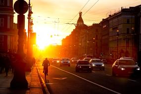 Beautiful cityscape with the cycler and cars on the road, at colorful sunset in the sky