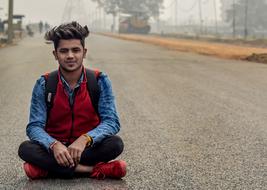 boy sitting on asphalt on a desert road