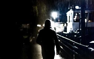 man in hoodie walking on embankment at night