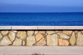 yellow stone Wall in front of blue Sea