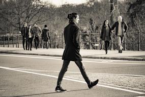 black and white photo of a man crossing the road