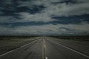 Beautiful landscape of the road, under the cloudy sky, among the fields in Mendoza, Argentina