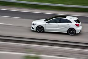 White car in motion, on the road, among the green plants