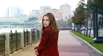 girl in a burgundy coat walks along the promenade