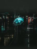 person with green umbrella on dark street