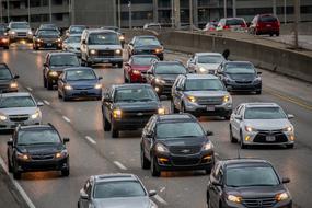 Cars with turning on headlights on wide road in city