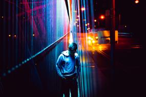 young Man walking alone on night street at colorful city lights