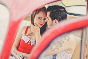 happy young couple in red car