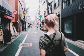 young girl walking away on street