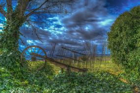 old wagon on a rural field against a stormy sky
