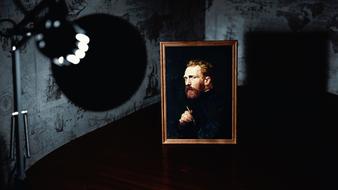 lamp illuminating van gogh portrait on table