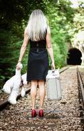 back view of sexy girl with teddy bear and suitcase standing on Railway