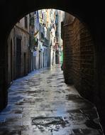 Beautiful, wet passage with the tunnel, among the colorful buildings, in the historic center of Barcelona, Spain