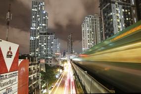 Skytrain, among the building, with the colorful lights, in motion, i Thailand