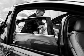 Black and white photo of the couple, getting into the shiny Wedding car