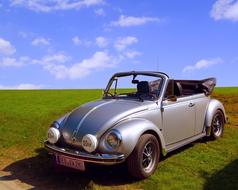 silver convertible on a field with green grass