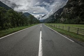 Beautiful road, among the green plants, on the mountains, under the blue sky with clouds