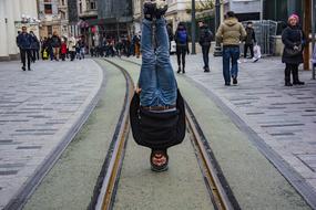 street performer stands on his head in the city street