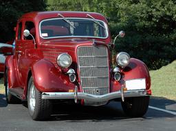 photo of a dark red retro car on an asphalt road