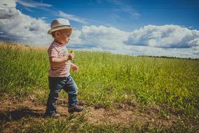 a child walks through a clearing with green grass
