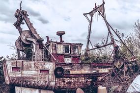 Close-up of the colorful, rusty, old boat, near the colorful plants, under the clouds