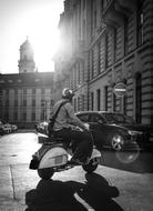 Black and white photo of the person on the scooter in light in Prague, Czech Republic