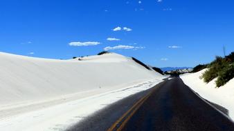 paved highway through white desert sands in america