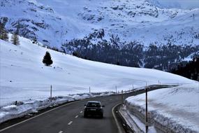 car on an asphalt road in the snowy alps