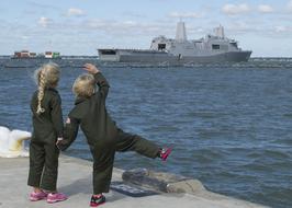 Children waving in the dock to the ship