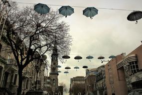 umbrellas hang between houses on the street